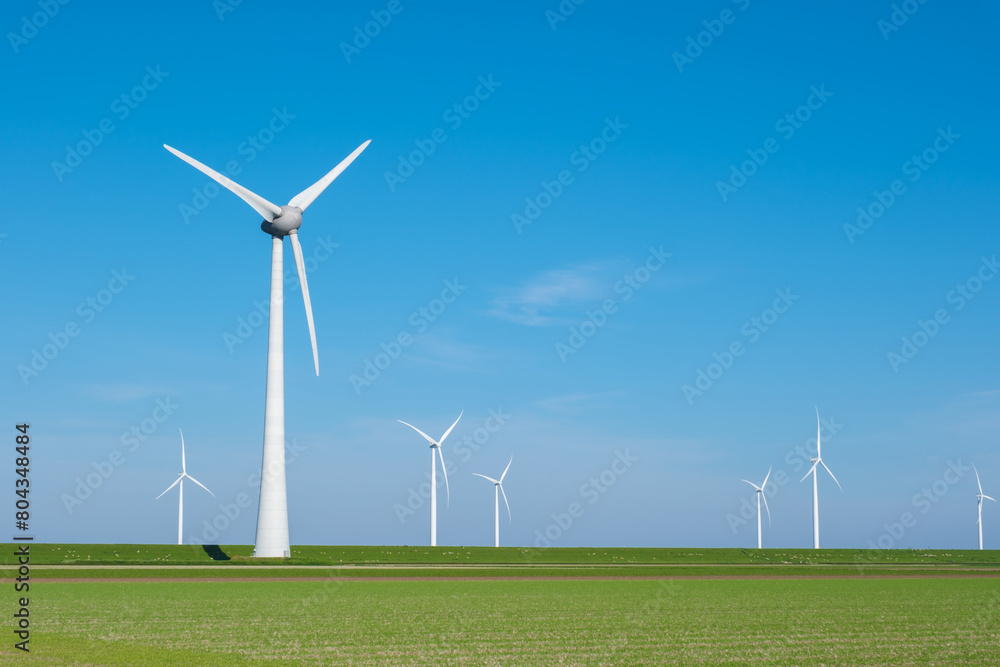 A group of elegant windmills stand tall in a lush green field in the Netherlands Flevoland, capturing the power of the wind to generate energy A group of elegant windmills stand tall in a lush green field in the Netherlands Flevoland, capturing the power of the wind to generate energy