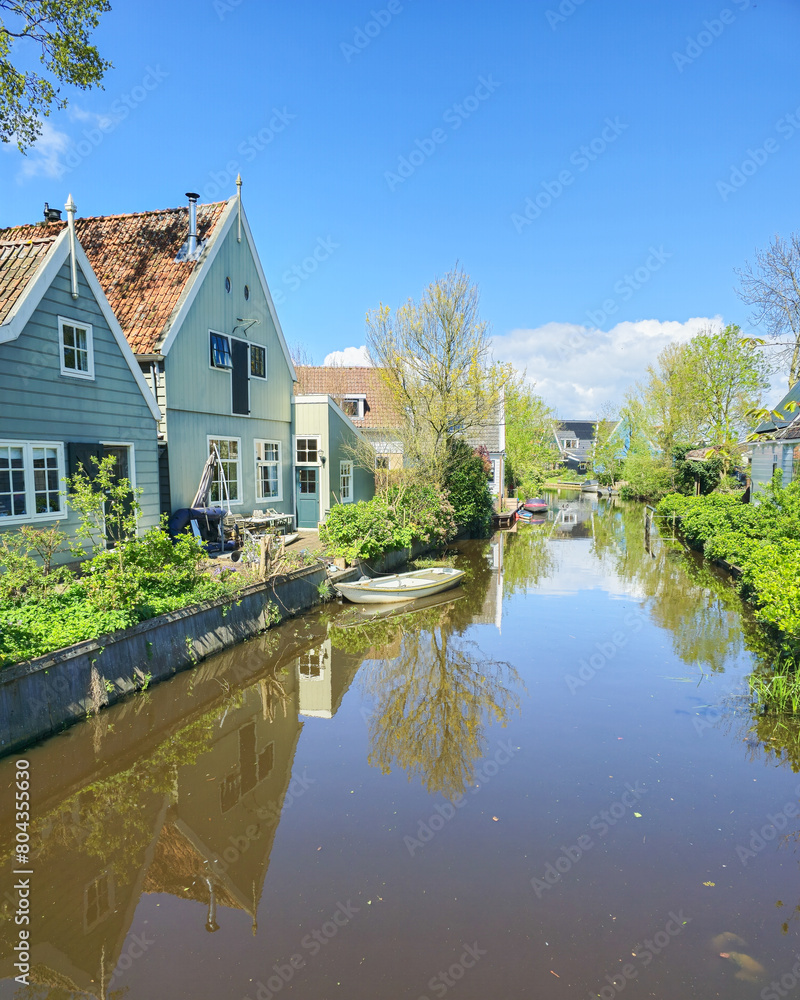 Obraz premium A peaceful river flows through a charming small town in the Netherlands, surrounded by traditional houses on either side