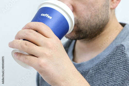 A man drinks from a plastic cup of coffee