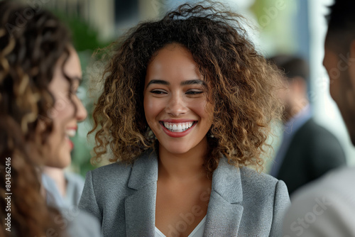 Joyful networking event. A cheerful young businesswoman engages in a light-hearted conversation with colleagues. Ideal for illustrating networking, teamwork, and corporate communication