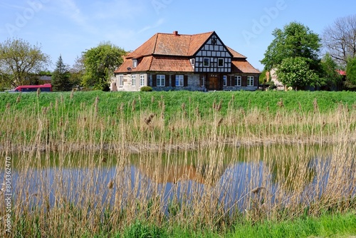 Landscape with Motlawa river and traditional building on bank of river, Ledowo, Zulawy Gdansk, Poland