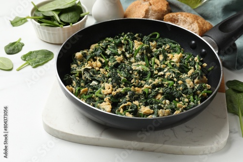 Tasty spinach dip with eggs in dish served on white table, closeup