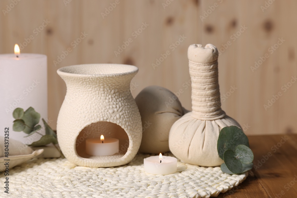 Obraz premium Different aromatherapy products, burning candles and eucalyptus leaves on wooden table