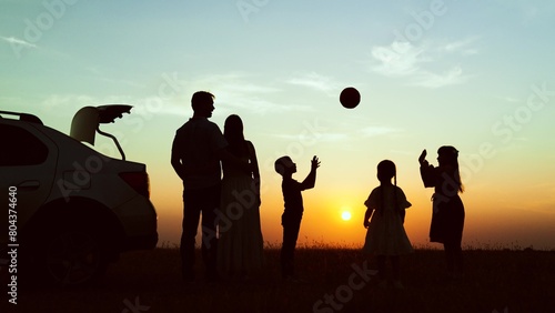 Silhouettes children parents at sunset near car in field. Family vacation in nature road trip picnic girls boys children kids parents dad mom in park. Journeys travelling road trip hiking picnic.