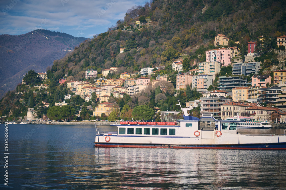 Beautiful touristic boat floating on a clean transparent water of the lake of Como in Italy, against beautiful alpine mountains background. Famous places concept. Travel destinations. Tourism. Trip. Beautiful touristic boat floating on a clean transparent water of the lake of Como in Italy, against beautiful alpine mountains background. Famous places concept. Travel destinations. Tourism. Trip.