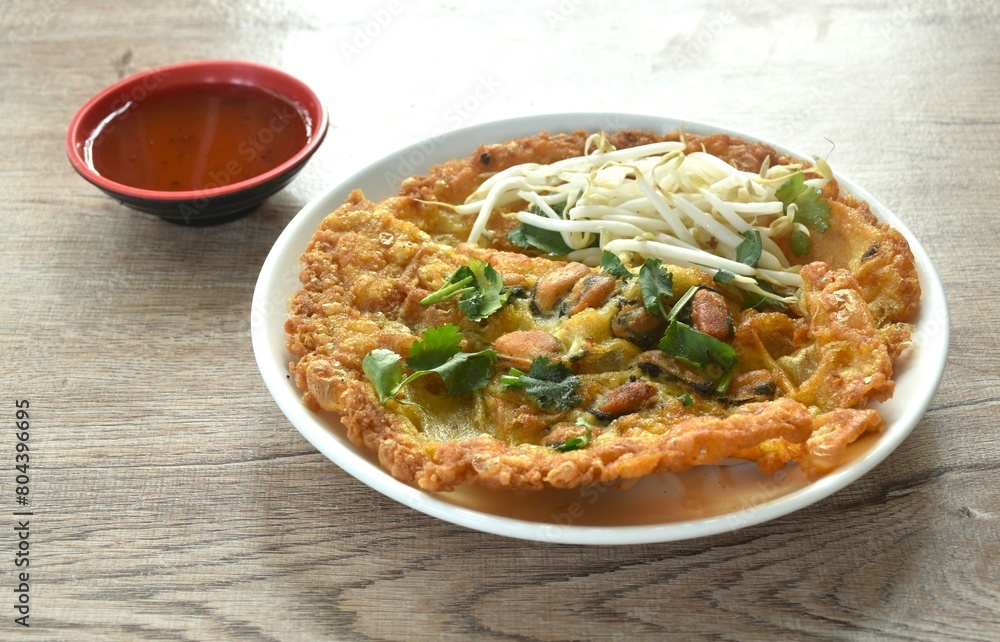 crispy fried egg and flour stuffed mussel with bean sprout on plate dipping chili sauce