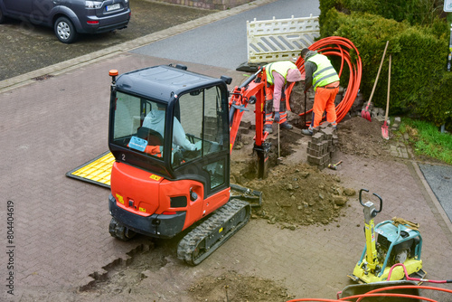 Die Arbeiter verlegen das Glasfaserkabel für das schnelle Internet auch bei schlechtem Wetter routinemässig photo