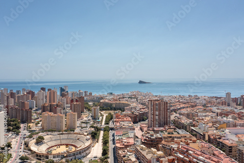 Aerial photo of the town of Benidorm in Spain showing buildings and apartments in the town and the old historical bull ring known as The Plaza De Toros Benidorm with the ocean in the background