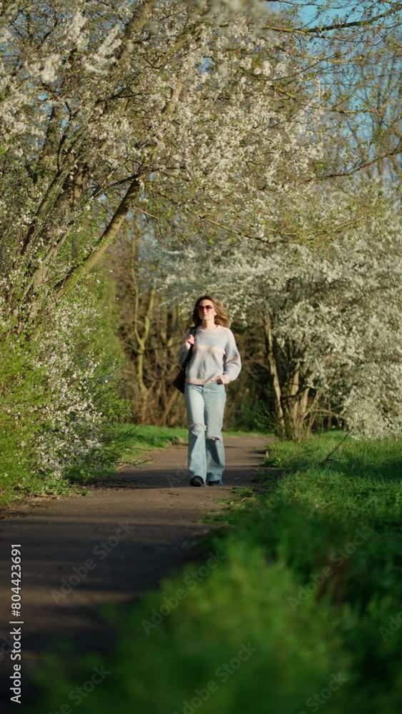 Young woman walking under cherry tree, enjoying blossoming of trees. Young woman walking under cherry tree, enjoying blossoming of trees.