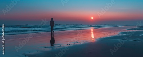 Lone person viewing the moon rise on the beach