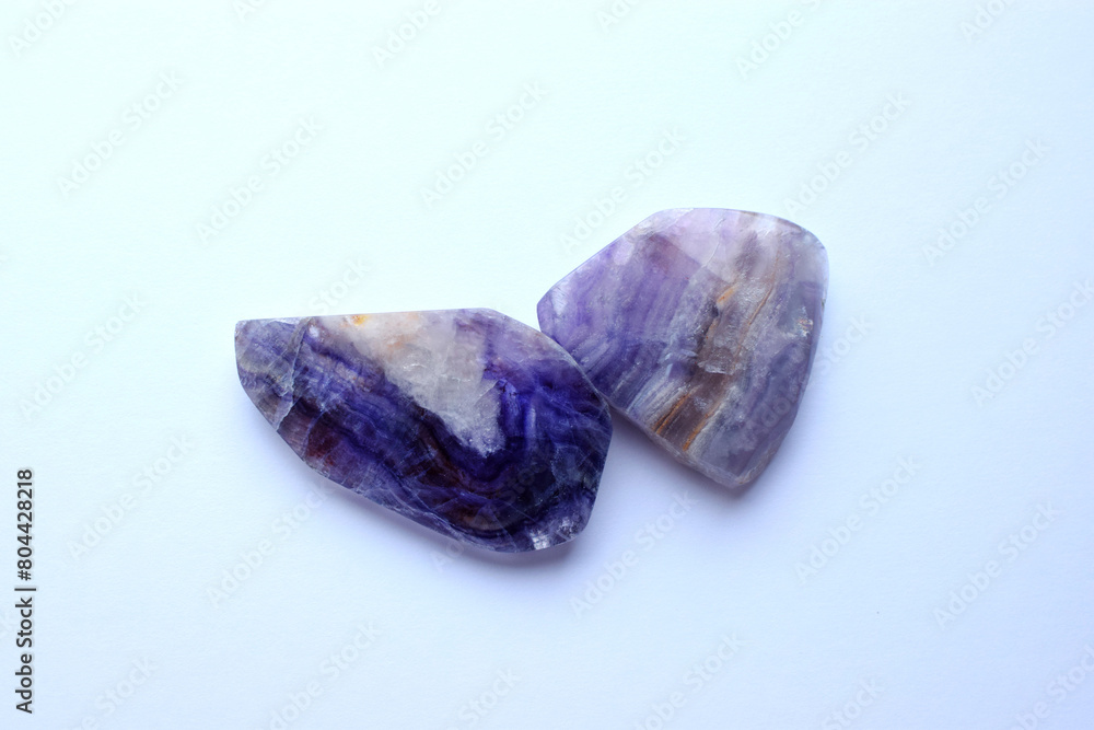 Close-up sections of beautiful striped purple fluorite on a white background. Healing Chakra Crystals Close-up sections of beautiful striped purple fluorite on a white background. Healing Chakra Crystals