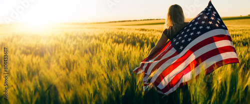 America celebrate 4th of July. Independence Day. Young woman holding bengal fire with American flag at sunset.	
 photo