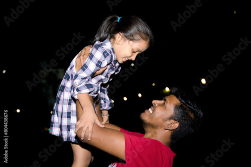 Father and daughter playing together in the park at night Concept of friendly family