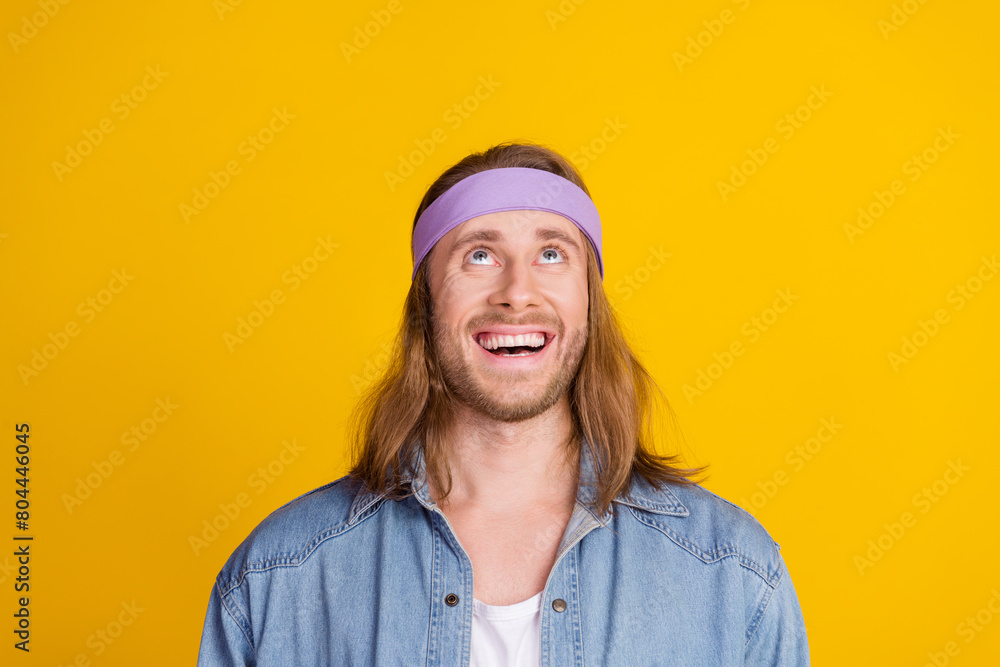 Photo portrait of attractive young hippie man look up excited empty space wear trendy denim outfit isolated on yellow color background Photo portrait of attractive young hippie man look up excited empty space wear trendy denim outfit isolated on yellow color background