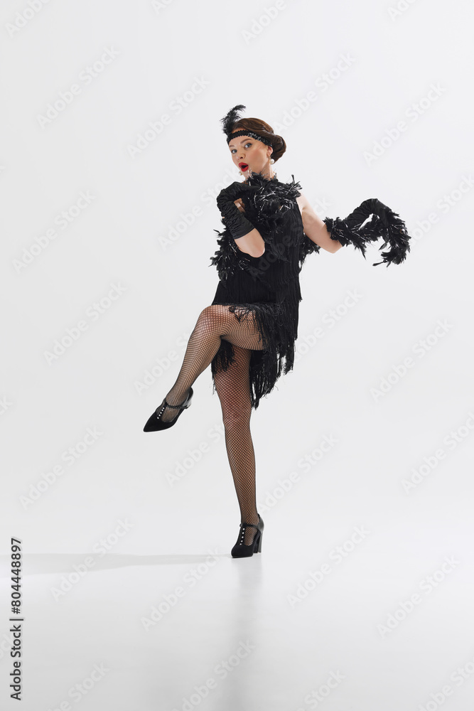 Solo female performer, beautiful woman in a 1920s flapper costume dances energetically isolated over white studio background. Concept of art, retro and vintage, hobby, entertainment, 20s Solo female performer, beautiful woman in a 1920s flapper costume dances energetically isolated over white studio background. Concept of art, retro and vintage, hobby, entertainment, 20s