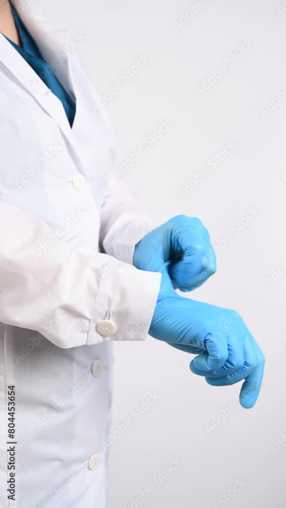 The doctor puts on latex gloves on a white background. Vertical video. The doctor puts on latex gloves on a white background. Vertical video.