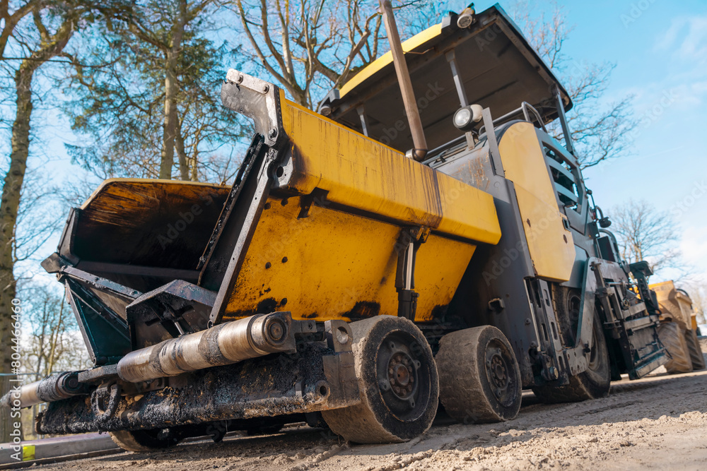 Fototapeta premium Big Asphalt paver with hot tarmac laying new road construction site 