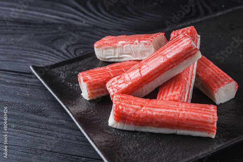 Tableau sur toile fresh chilled surimi crab sticks on black wooden background