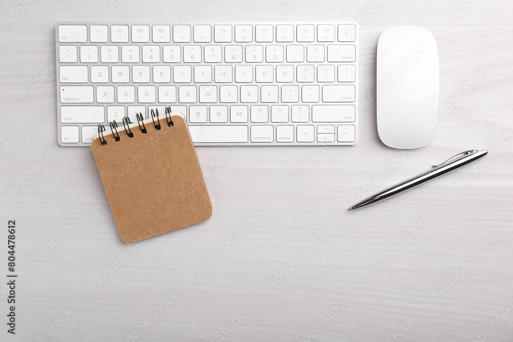 Office workplace. Keyboard, pen, mouse and notebook on white wooden table, flat lay. Space for text Office workplace. Keyboard, pen, mouse and notebook on white wooden table, flat lay. Space for text