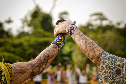 Sao Paulo, SP, Brazil - April 20 2023: Women holding hands in the air, painted arms and colorful traditional indigenous bracelets details.