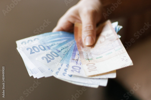 Hand holding Moroccan banknotes, dirham official currency of Morocco.