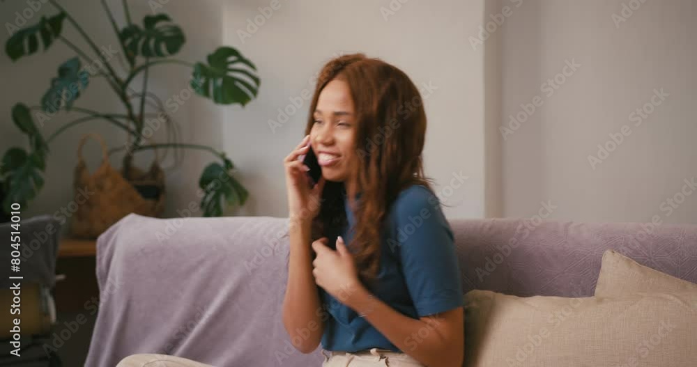 Joyful Latin lady talks on mobile phone in living room Joyful Latin lady talks on mobile phone in living room