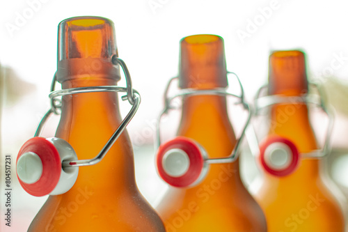 Bottle neck with bugel plug. A row of brown glass bottles held up to the light. photo