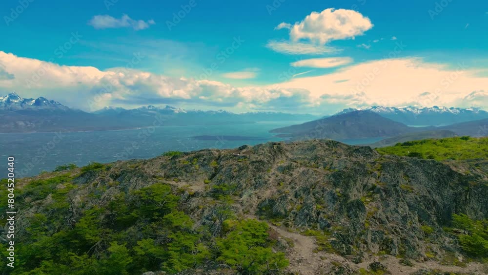 A couple tourist stand on mountain peak overlooking the Beagle Channel at windy day in Ushuaia, Tierra del Fuego, Argentina. Aerial drone video. A couple tourist stand on mountain peak overlooking the Beagle Channel at windy day in Ushuaia, Tierra del Fuego, Argentina. Aerial drone video.