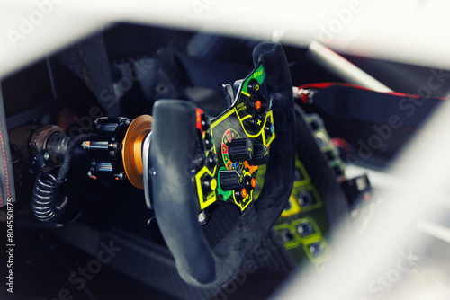 Detailed view of a high-tech racing car steering wheel, gear shift controls and settings. Interior professional race car drivers technology engineering speed in motorsport competition photo