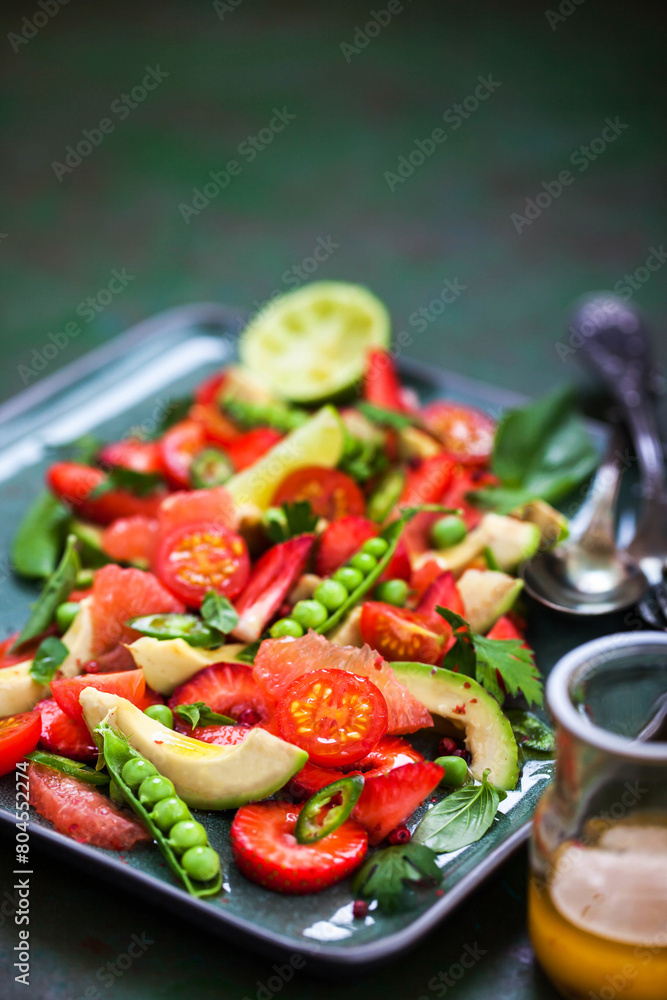 Spring salad witn avocado, tomato, strawberry, grapefruit, green pea and herbs