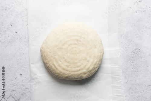 Overhead view of sourdough bread dough about to be baked, artisan bread dough on parchment lined baking tray, process of making homemade bread photo