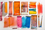 A variety of watercolor squeegees and palette knives, each for unique textural effects, on a white canvas.