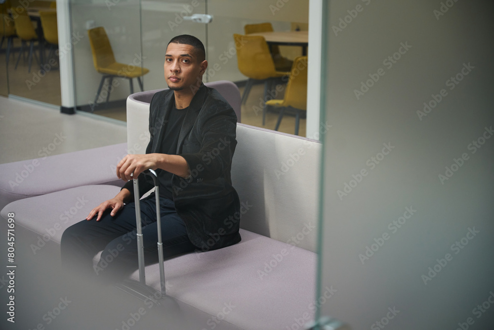 Calm male employee sitting on sofa in business center Calm male employee sitting on sofa in business center