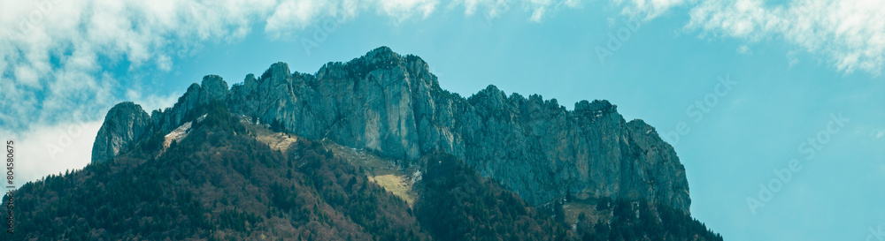 Fototapeta premium Aerial view of mountains and green landscapes around the castle of Menthon-Saint-Bernard, paths surrounded by greenery and snow-capped peaks. in the Haute-Savoie department of France.