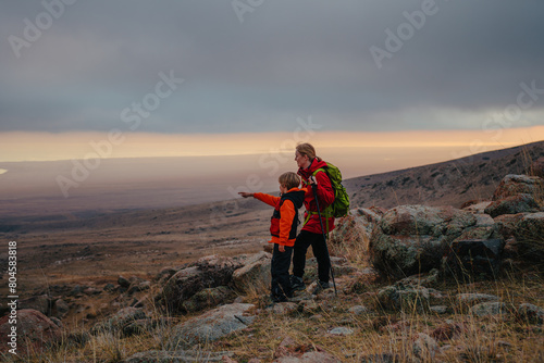 Woman tourist with son standing on the mountain and looking out into the distance