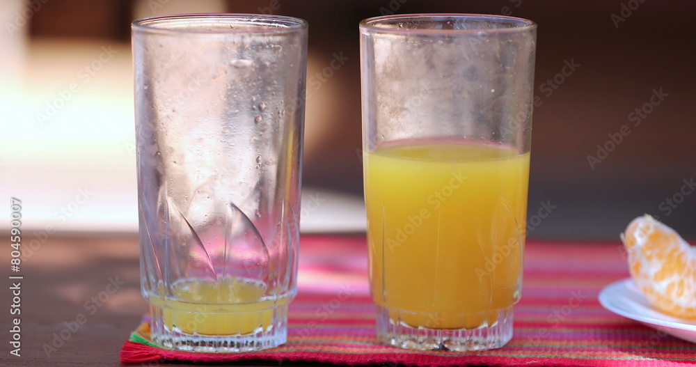 Empty and half full glass of orange juice Empty and half full glass of orange juice