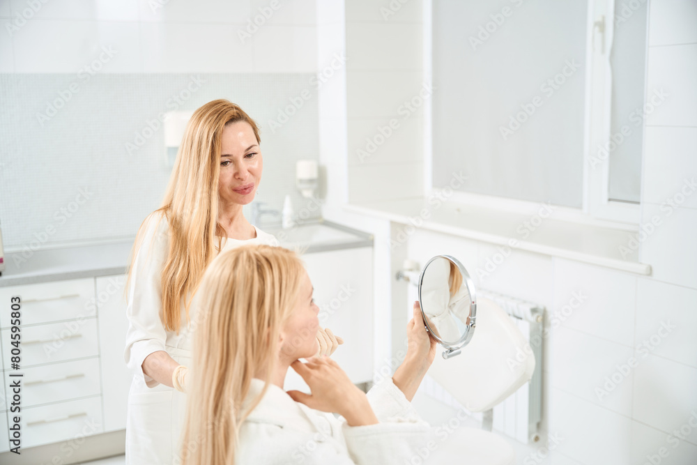 Woman client satisfied with her face oval modelling and chin contouring Woman client satisfied with her face oval modelling and chin contouring