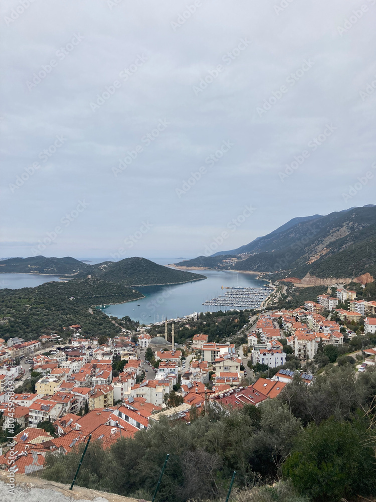 The city view of Kas with red roof houses, marina and mountains