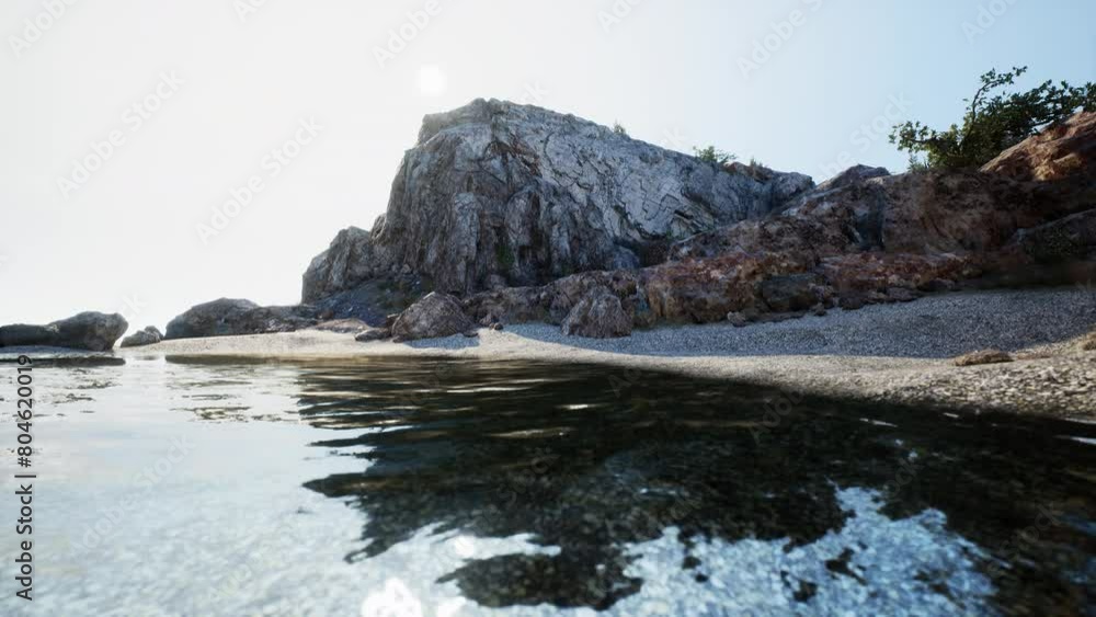 A picturesque rocky beach with crystal-clear water and a majestic mountain in the background in Spain. A picturesque rocky beach with crystal-clear water and a majestic mountain in the background in Spain.