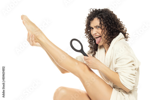 Disgusted woman looking a hair on her legs on a white background
