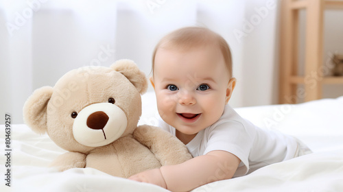 close-up 5 month old baby holds a toy in his hands lying on a white blanket in a bright room on the left,