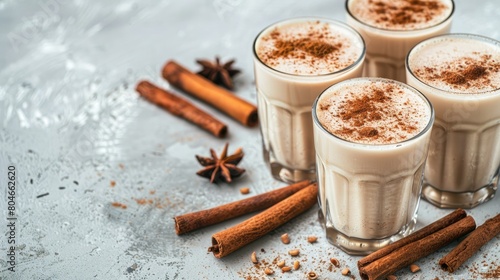 glasses of white coconut milk infused with cinnamon, set against a dark grey background, offering a visually appealing contrast and leaving ample space for text.
