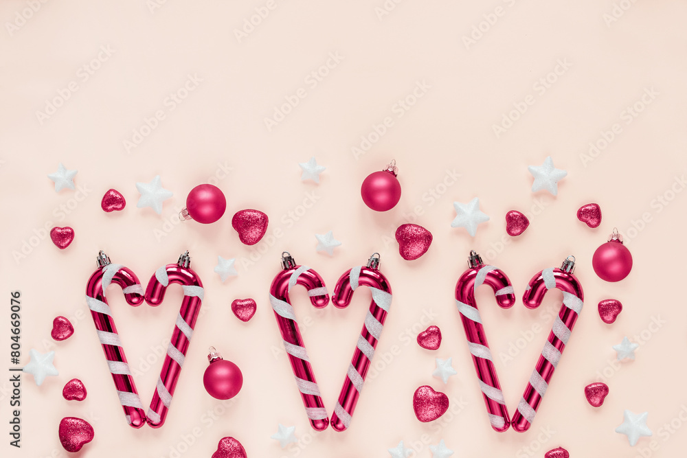 Christmas themed arrangement with candy canes, pink balls, star decorations pastel pink background Christmas themed arrangement with candy canes, pink balls, star decorations pastel pink background