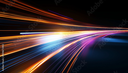 Colorful light streaks blur across a highway at night, creating an abstract motion effect