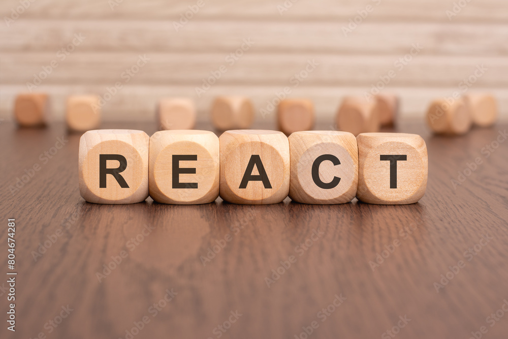 the text 'REACT' is written on wooden cubes on a brown background the text 'REACT' is written on wooden cubes on a brown background