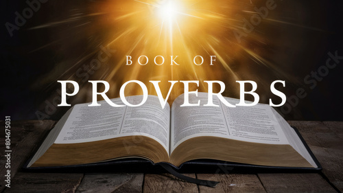 Open Book of Proverbs on a wooden table illuminated by bright light creating a mystical atmosphere photo