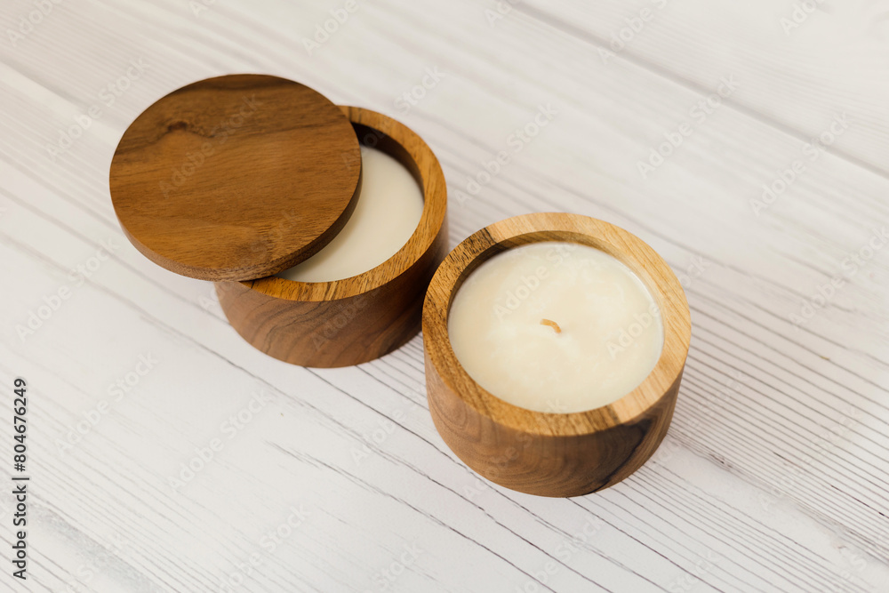 A candle in a wooden box. A candle on a white table. A candle in a wooden box. A candle on a white table.