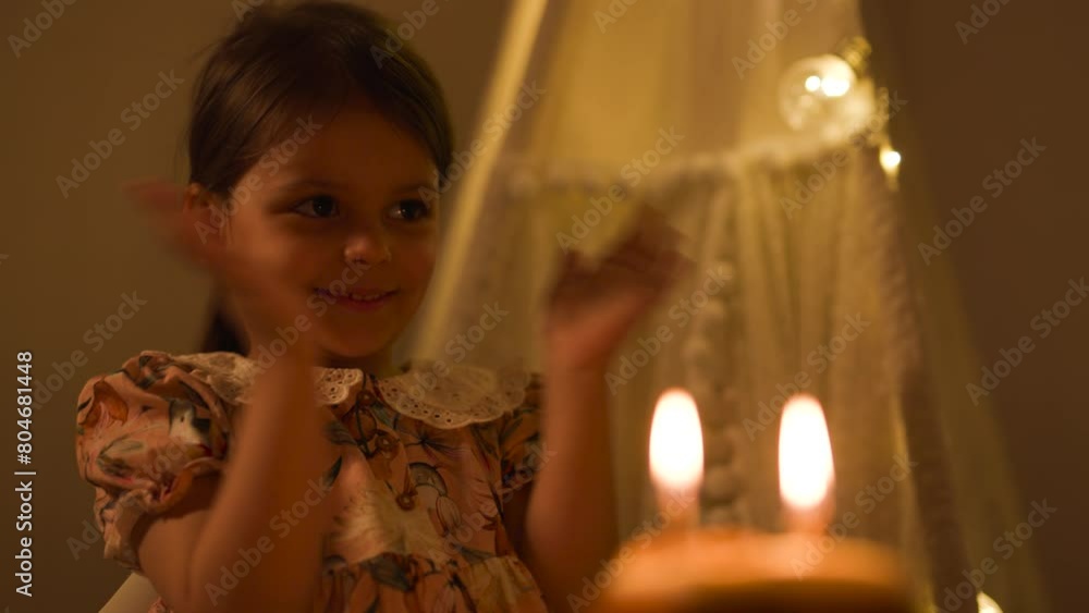 Happy child looks at a cake with candles. Girl celebrates birthday. Happy child looks at a cake with candles. Girl celebrates birthday.