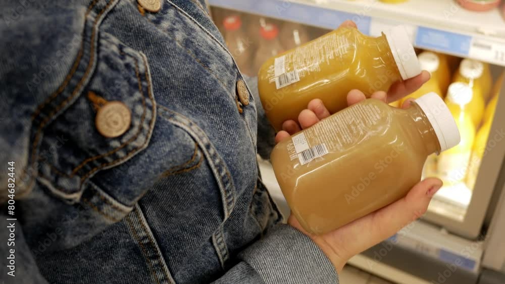 Little girl hands selects fresh squeezed juice In plastic bottle at