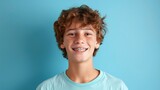 Portrait of emotional teenage boy with braces smiling against plain blue background